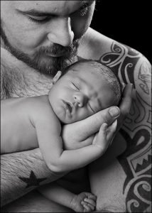 tattooed dad cradling his newborn son