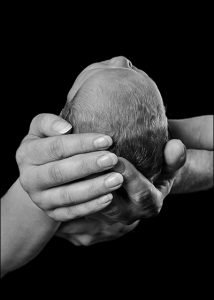 parents hands cupping baby's head