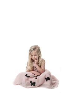 little girl in a pink dress sat looking at the floor