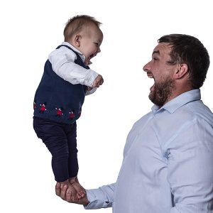 dad holding his young son in one hand - both are laughing