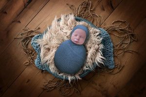baby wrapped in blue swaddling